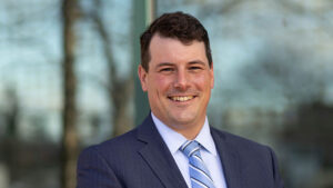 Portrait photo of man outdoors with trees in background.