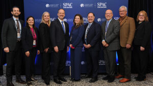 Albany Med Health System leadership and board members stand in front of a banner at the announcement of the Albany Med Health System partnership with SPAC Live Nation