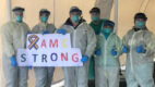 Albany Med employees wearing personal protective equipment hold a sign reading "AMC Strong" in the midst of the Covid pandemic