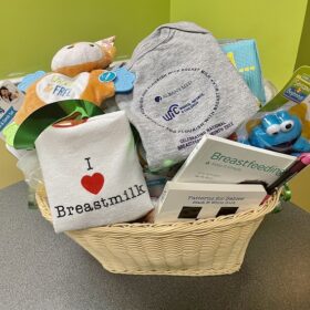 Basket of breastfeeding books, infant toys, and t-shirts
