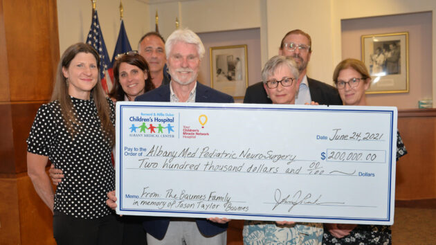 Alan and Nancy Taylor Baumes, joined by members of their family, presented a check for $200,000 in support of Pediatric Neurosurgery at the Bernard & Millie Duker Children’s Hospital in memory of their late son, Jason Taylor Baumes