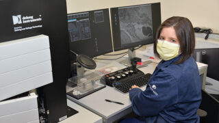 Andrea Lightle, DO, sits in front of an electron microscope reading scans