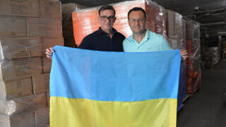 Dr. Vadim Vaisman and Dr. Gennady Bratslavsky holding the Ukrainian flag surrounded by medical supply donations.