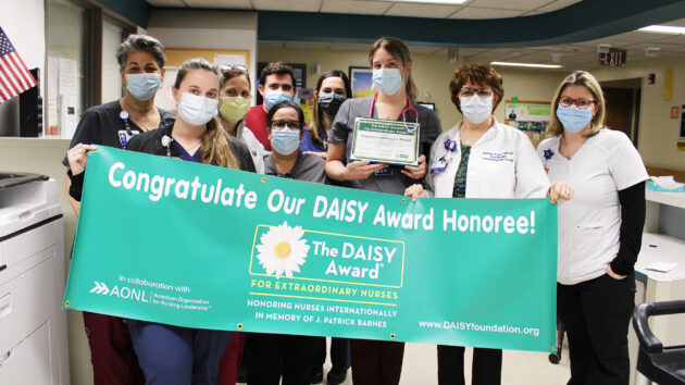D4E staff hold DAISY Award banner to recognize nurse Angelique Sanderson, RN, February 2022