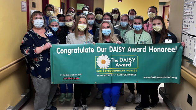 D7 staff hold a DAISY Award banner recognizing nurse Bree Ford, RN