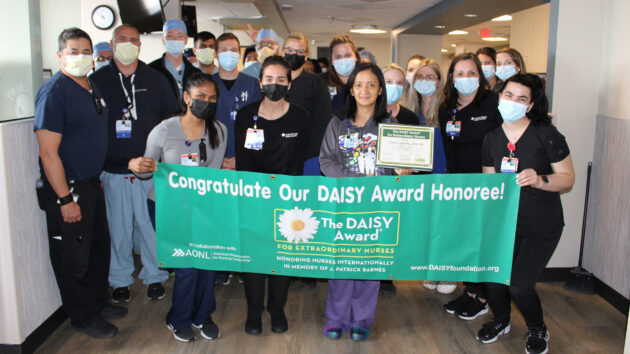 Cardiac Cath Lab stuff hold DAISY Award banner honoring nurse Cherry Navalta, RN