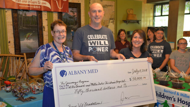 Dr. Joanne Porter accepting a check from Matt and Tammy Hladun on behalf of the Brave Will foundation in Camp Amedore at the Bernard and Millie Duker Children's Hospital