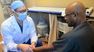 Dr. Michael Mulligan examines the wrist of a patient.