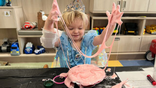 A young girl dressed as a princess makes pink slime