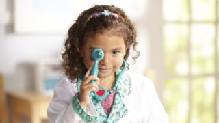 A young girl dressed as a doctor with toy medical equipment. Prescriptions for Play