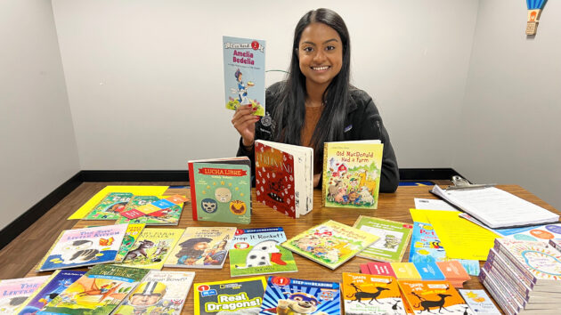 Medical student sitting at a table full of children's books, in the General Pediatrics office