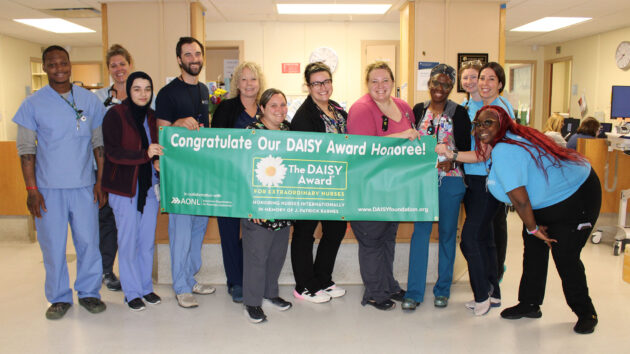 Andrea Frascello, E4, General Medicine unit and team hold the DAISY Award banner