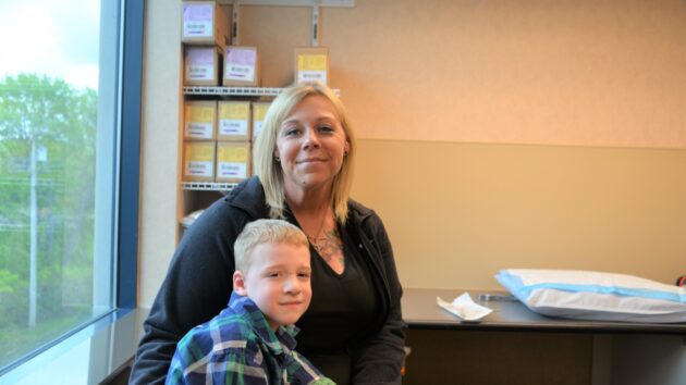 Kevin McGuire, a 5-year-old patient, sits with his mom, Melissa Heddy, in an exam area of the Bone & Joint Center in Albany.