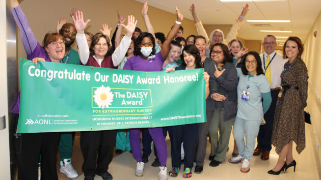 Nurse Kenyatta Hyman, RN, and the POCU team hold up the DAISY Award banner