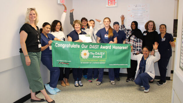 Patty McLaughlin, RN, and the Digestive Diseases Center hold the DAISY Award banner.