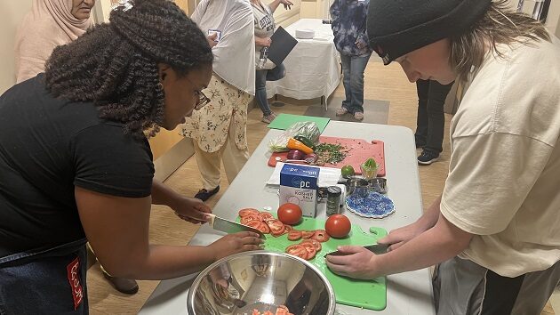 Two people chopping tomatoes to make salsa