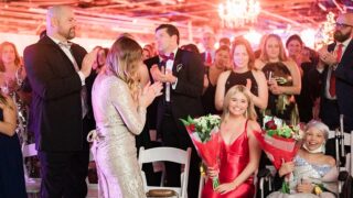 crowd applauds two Melodies Center patients, holding flowers, at Dancing in the Woods 2023