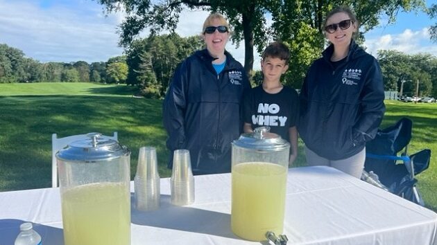 two woman and a boy selling lemonade at the annual golf tournament