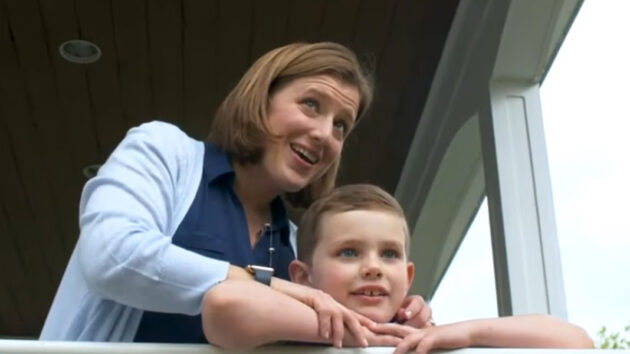 Mother and young son looking into the distance over a porch railing