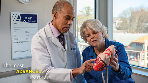 Provider discusses with patient while using heart model for reference.