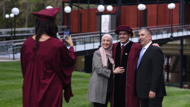 Albany Medical College graduate taking a photo of another graduate and his family at 2024 Commencement ceremony