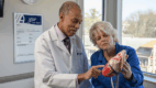 A doctor points to a portion of a heart model while discussing results with a seated patient.