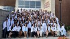 A new class of medical students in white coats, sitting on the steps of Albany Medical College