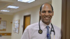Dr. Tej Gonuguntla standing near a door with a stethoscope around his neck