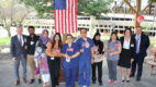 A dozen employees in front of a flag during the citizenship day ceremony