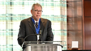 Dr. Jeffrey Friedman speaking at a podium to accept the 2025 Albany Prize