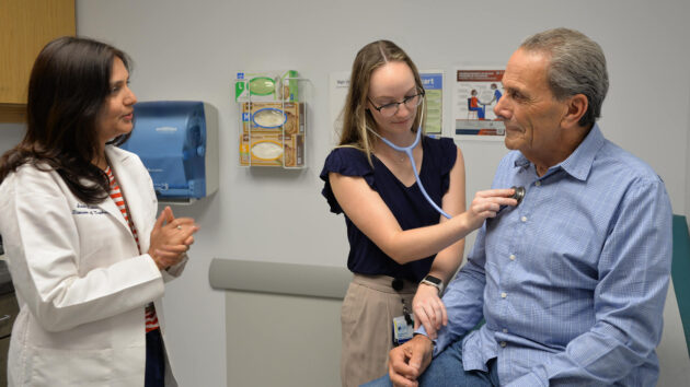 Glomerular disease patient Charles Batchelor is examined in an exam room by internal medicine resident Dr. Jordan Loon while he talks with his doctor, Dr. Swati Mehta