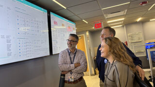 Three people looking at screens of data that show hospital census in real time.