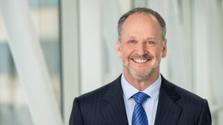 image of Dan Pickett in blue suit on pedestrian bridge