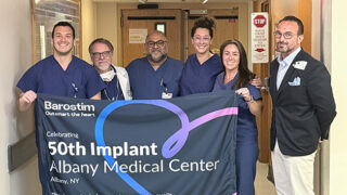 Members of the team that performed the 50th Barostim procedure hold a banner celebrating their milestone.