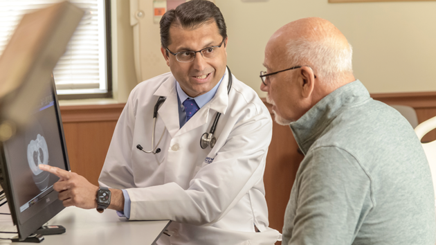 A doctor points to a medical image while talking to a man