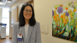 Urologist Dr. Lara MacLachlan standing next to a painting of flowers in a hallway in the urology clinic
