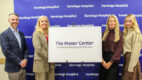 Donation ceremony attendees holding a sign reading, "The Moser Center for Successful Aging & Wellness."